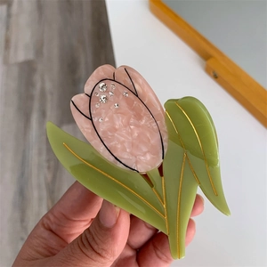 Dettaglio del fermaglio per capelli a tulipano in acetato rosa con strass scintillanti