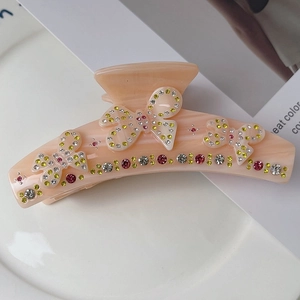 Détail de la pince à cheveux papillon avec strass et finition marbrée orange