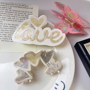 Trois pinces à cheveux en acétate avec motifs lettre d'amour et papillon sur assiette