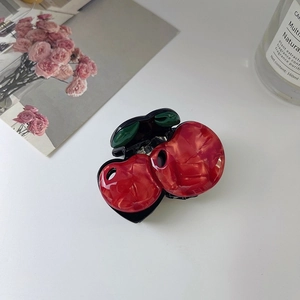 Détail d'une pince à cheveux cerise 3D en acétate avec un motif texturé marbré