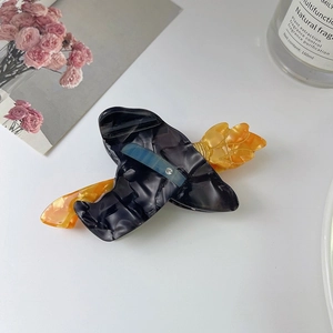 Détail d'une pince à cheveux Halloween avec chapeau de sorcière noir et balai orange