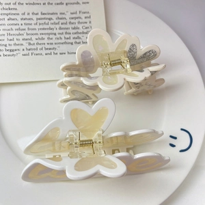 Détail de pinces à cheveux bicolores en acétate avec motifs floraux sur livre vintage