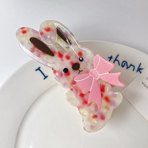 Détail de la pince à cheveux lapin en acétate avec nœud rose et texture marbrée élégante