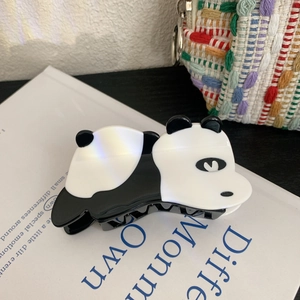 Detail einer süßen Panda-Haarklammer in Schwarz-Weiß-Optik auf einer Buchoberfläche