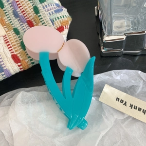 Dettaglio della molletta per capelli a forma di tulipano rosa e blu su carta stropicciata