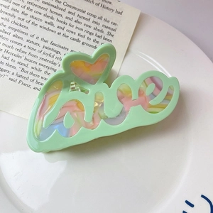 Détail de la pince à cheveux en acétate vert avec motif marbré coloré et texte LOVE