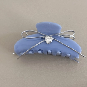 Detail of light blue acetate hair claw with silver ribbon bow and heart crystal