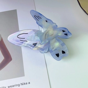 Vue détaillée d'une grande pince à cheveux papillon en acétate violet dégradé avec cœurs