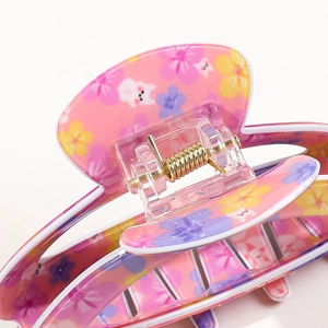 Detailansicht der rosa Acryl-Haarklammer mit Blumenmuster und goldener Metallfeder