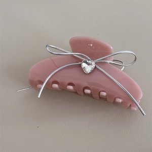 Detailed macro view of the pink hair claw clip with a silver ribbon bow and heart crystal