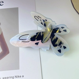 Vue macro d'une pince à cheveux papillon en acétate nacré avec motif cœur découpé