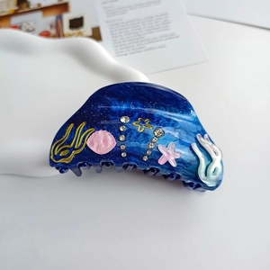 Detailed shot of dark blue marble hair claw with pink seashell and starfish accents