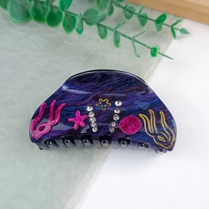 Detail view of marble-textured ocean theme hair claw clip with rhinestones and starfish decor