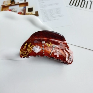 Detailed macro shot of tortoiseshell shark hair claw with seashell and rhinestone accents