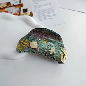 Detail of ocean-themed hair claw clip with marble texture, seashell and starfish accents