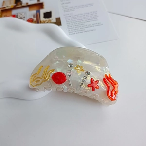 Macro shot of seashell and starfish decorations on a translucent cream white hair claw