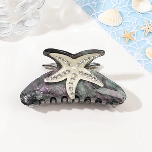 Détail de la pince à cheveux marbrée avec étoile de mer en strass et perle