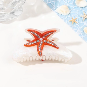 Détail de la pince à cheveux étoile de mer avec strass et perles sur décor bleu marine