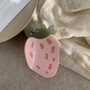 Détail de la pince à cheveux fraise rose en acétate avec des strass sur les feuilles vertes
