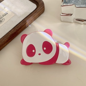 Detail of pink and white acetate panda hair claw clip on a minimal desktop setting