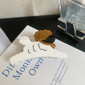 Détail d'une pince à cheveux mignonne en acétate motif chien teddy sur livre déco