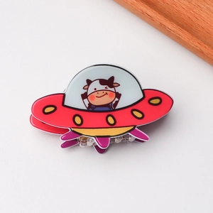 Detail shot of the red UFO cartoon hair claw with a cute cow design and metal teeth