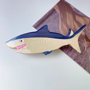Macro shot of creative shark-shaped hair claw with smooth navy and beige acetate finish