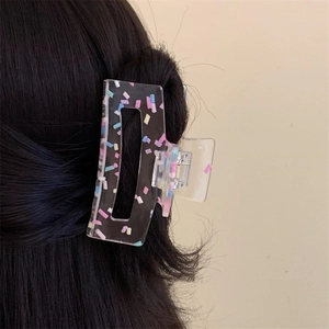 Close-up of translucent black hair claw with colorful dots worn on dark long hair