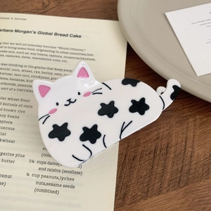 Close-up of a cute black and white cow cat hair claw clip on a rustic wooden table
