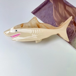 Detail of shark-shaped acetate hair claw clip with stylish brown marble fin texture