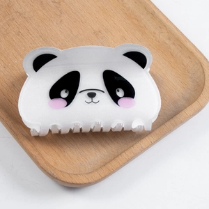 Nahaufnahme einer süßen Panda-Haarklammer mit glitzerndem Acryl auf Holztablett