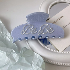 Detailed macro view of a lavender acetate hair claw with delicate pearl BeBe lettering