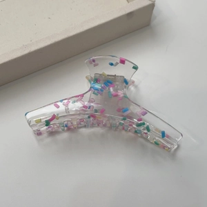 Detailed close-up of transparent hair claw clip with colorful candy-colored dotted accents