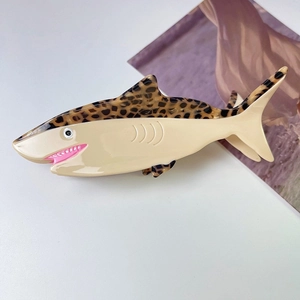 Close-up of shark-shaped hair claw clip with leopard pattern and spring grip detail