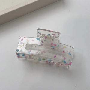 Macro shot of rectangular acrylic hair claw clip with colorful candy dots and metal spring