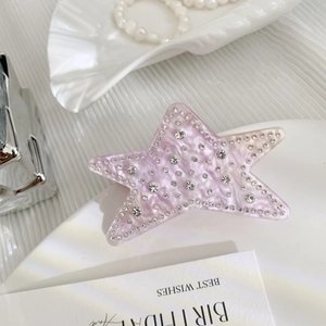 Detailed macro view of pink star acetate hair claw clip with rhinestones and marble texture