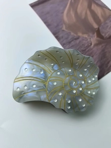 Detailed view of sea shell hair claw clip with pearlescent finish and gold spiral patterns