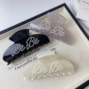Three elegant pearl-lettered acetate hair claws in black, lilac, and cream for ballet style