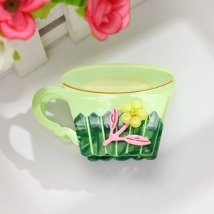 Détail d'une pince à cheveux en forme de tasse de café vert clair au motif floral