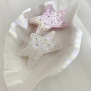 Star-shaped acetate hair claws with sparkling rhinestones in purple and ivory white