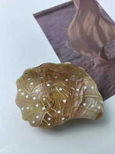 Macro detail of amber marble shell hair claw with golden spiral engraving and white inlays