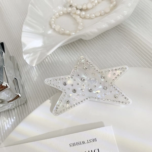 Detailed close-up of a star-shaped hair claw with sparkling rhinestones and pearl finish