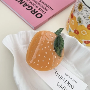 Detailed view of acetic acid fruit shape hair claw clip on an aesthetic white ceramic tray