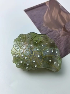 Detail of seashell hair claw clip with green translucent finish and golden spiral lines