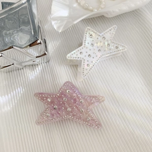 Sparkling star-shaped acetate hair claws with rhinestones in iridescent white and lilac purple