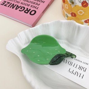 Detailed view of a green acetic acid lemon hair claw clip on a stylish ceramic tray
