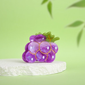 Dettaglio della molletta per capelli a forma di uva viola con accenti di foglie verdi