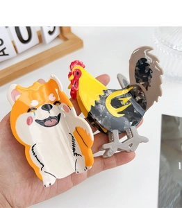 Detailed view of handmade acetate hair claws featuring Shiba Inu and rooster animal designs