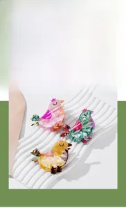 Detail of bird-shaped acetate hair claws with marble texture in pink, green and yellow