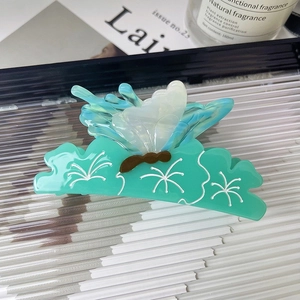 Close-up of butterfly hair claw clip with mint green base and iridescent blue wings